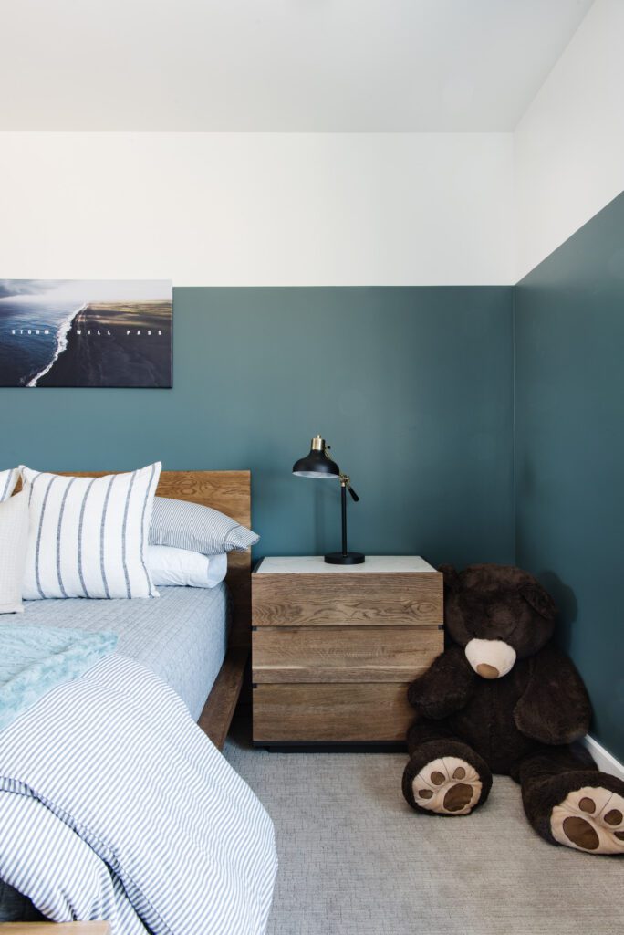 Bedroom with color block wall top 1/3 of the wall is white bottom 2/3 of the wall is teal