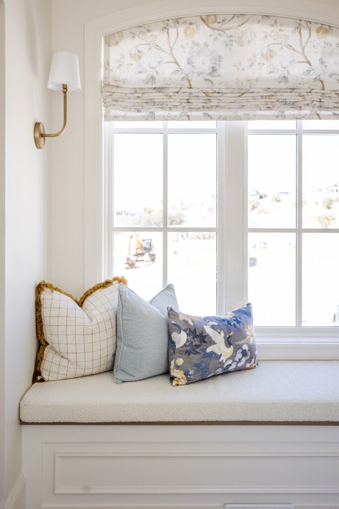 In home window seat featuring roman shades and pillows