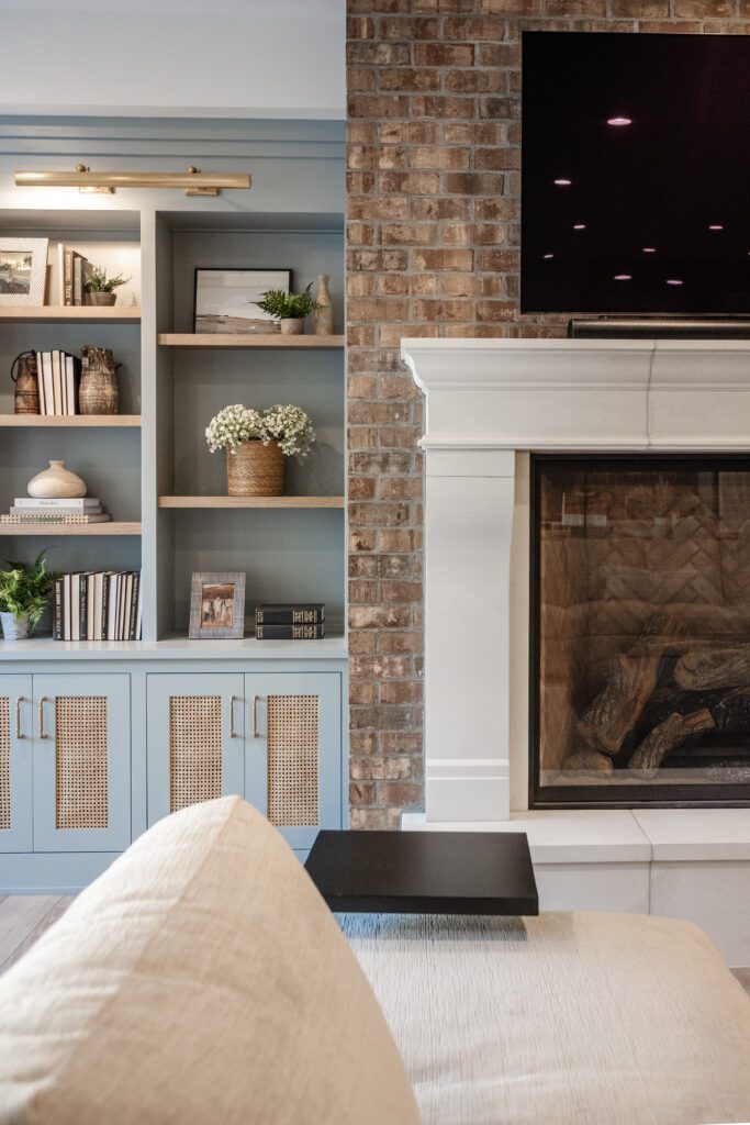 Silvery blue cabinetry contrasting with a real brick fireplace